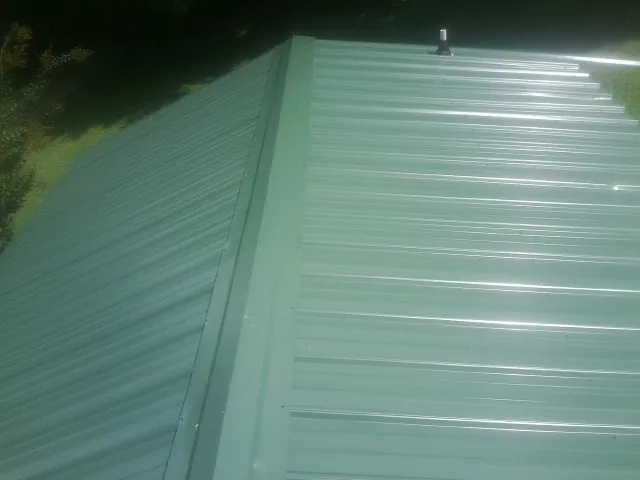 New green metal panels meeting at the ridge of a roof — Flat Roof Repair work by our crew in Franklin